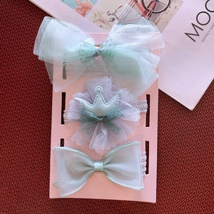 Detailed view of three mint green baby headbands with tulle bows and crown on a pink card