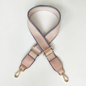 Detail of adjustable canvas bag strap with pink and grey stripes and gold hardware