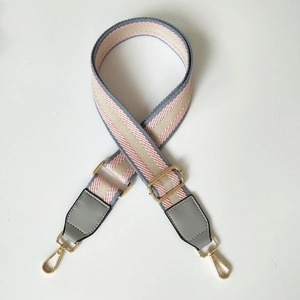 Adjustable striped fabric strap with grey leather ends and gold metal buckles