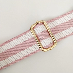 Close-up of pink and white striped bag strap with adjustable gold metal buckle