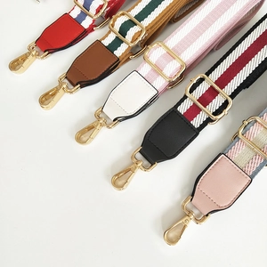 Detail of adjustable canvas bag straps with colorful stripes and gold metal hardware