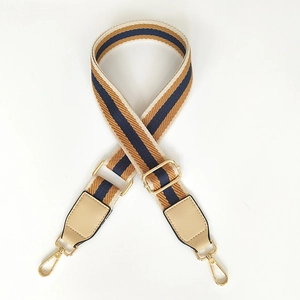 Detail of adjustable striped woven strap with beige leather ends and gold metal hooks