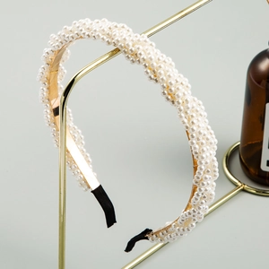 Detail of elegant white faux pearl headband with a gold frame and black end tips
