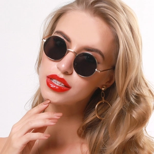 Close-up of retro silver round metal sunglasses with black lenses on fashion model