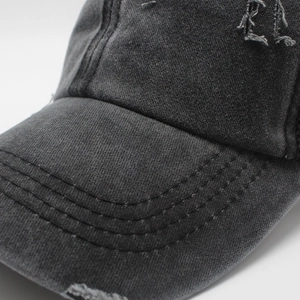 Dettaglio ravvicinato del cappellino grigio antracite con bordi sfrangiati e tela lavata