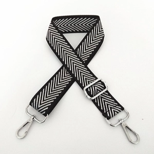 Detail of black and white herringbone nylon bag strap with silver metal hooks and buckles