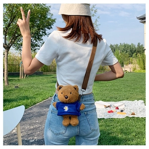 Outdoor view showing the back profile of the cute brown plush bear crossbody bag with strap