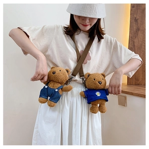Detail of cute plush teddy bear bag featuring blue overalls and daisy pattern shirt