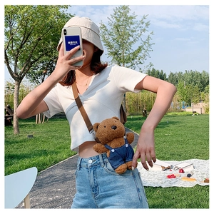 Detail of cute plush bear crossbody bag with denim overalls and adjustable strap