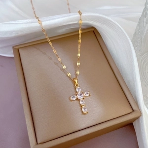 Elegant gold titanium steel cross necklace with pavé zircon stones on jewelry box