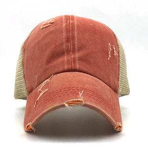 Close-up of distressed red washed cotton baseball cap with khaki mesh and worn holes