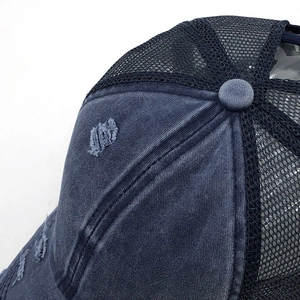 Close-up of washed blue cotton stitching and mesh detail on a distressed ponytail baseball cap