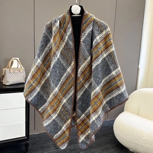 Detail of soft knit plaid shawl with grey and yellow checkered pattern hanging on a hanger