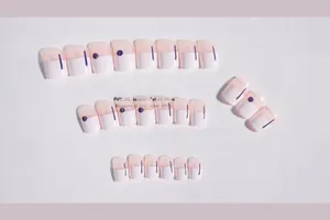 Detailed flat lay of French press-on nails with white tips and purple dotted accents