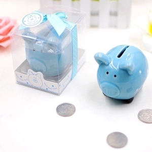 Cute blue piggy bank with white polka dots in a gift box with a blue ribbon bow
