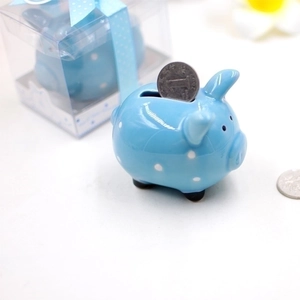 Blue ceramic piggy bank with white polka dots and a coin being inserted into the slot