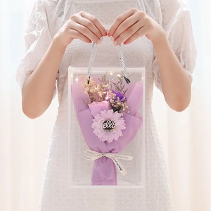 Purple soap rose bouquet with LED lights in a transparent PVC gift bag held by hands