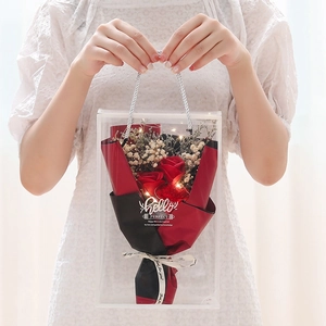 Close-up of soap rose bouquet in transparent gift box with LED lights and red paper