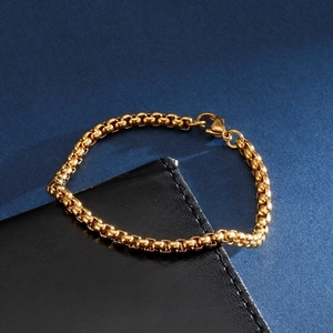 Detail of gold-plated box chain titanium bracelet with secure lobster clasp on leather