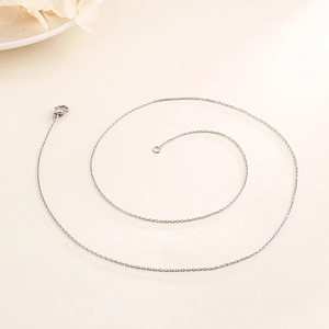 Detail of silver O-chain necklace featuring a secure lobster clasp on a beige background