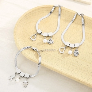 Detailed shot of silver snake bone bracelets with heart and pearl charms on wood tray