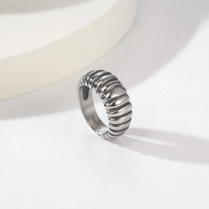 Minimalist silver croissant textured stainless steel ring on a round geometric display stand