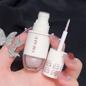 Dettaglio dell'ombretto liquido rosa glitterato con applicatore e texture brillante scura
