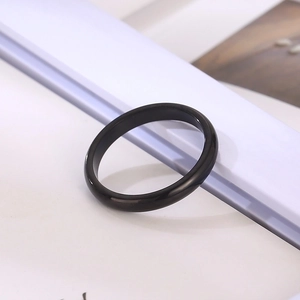 Close-up of minimalist black polished ring band displayed on an elegant white book