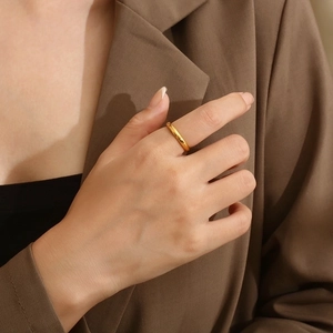 Minimalist 3mm golden stainless steel domed ring worn by a model in elegant attire