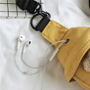 Détail du sac de poitrine en toile jaune vif doté d'un port pour écouteurs dédié