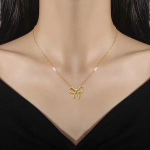 Minimalist gold bow pendant necklace in titanium steel on model collarbone