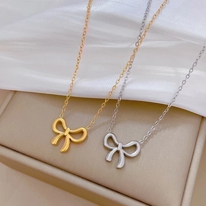 Minimalist titanium steel bow necklace set in gold and silver finish on soft fabric