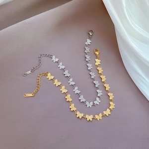 Detail of butterfly link bracelets in gold and silver finish with lobster clasp and tag