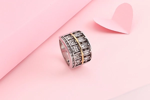 Macro shot of silver and gold stainless steel ring with white zircons on pink background
