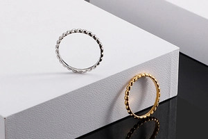 Detailed view of silver and gold beaded stackable titanium steel rings on white cubes