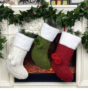 Détail de trois chaussettes de Noël en tricot avec bordure en peluche sur une cheminée