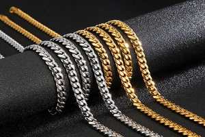 Detailed macro view of 8mm polished gold and silver Cuban link chains on black background