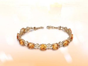 Detail view of gold bracelet featuring oval orange citrine stones and clover motifs