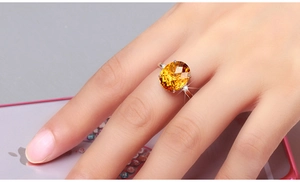 Detailed close-up of a large oval orange-yellow gemstone ring worn on a finger