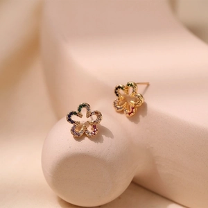 Rainbow cubic zirconia flower stud earrings in gold plating displayed on beige props