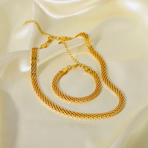 Detailed flat lay of 18K gold plated mesh weave necklace and bracelet set on silk