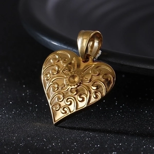 Detailed view of vintage engraved gold heart pendant with intricate scroll patterns