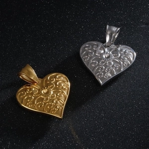 Detailed macro view of gold and silver heart pendants with intricate floral engravings