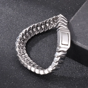 Macro detail of polished silver keel chain bracelet with wave pattern on gray sand texture