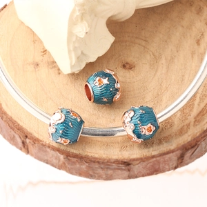 Macro shot of blue ocean charms featuring fish motifs and wave patterns in enamel