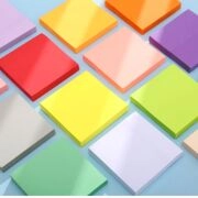 Flat lay of colorful square sticky notes in vibrant shades on a light blue surface