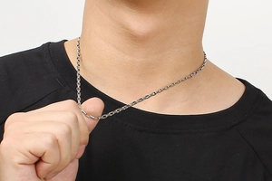 Close-up of a silver stainless steel rectangular link chain worn on a model neck