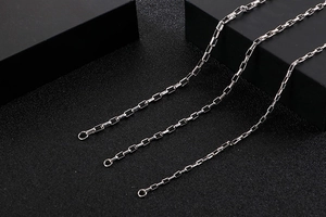Detailed view of silver stainless steel box chains on dark textured background