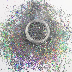 Holographic silver hexagonal nail glitter powder in a clear jar on white background