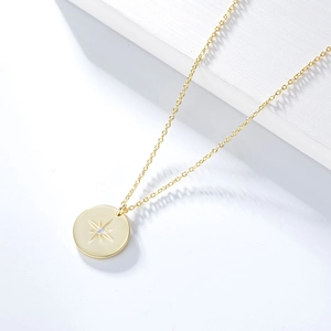 Close-up of golden S925 sterling silver coin necklace with star engraving and crystal